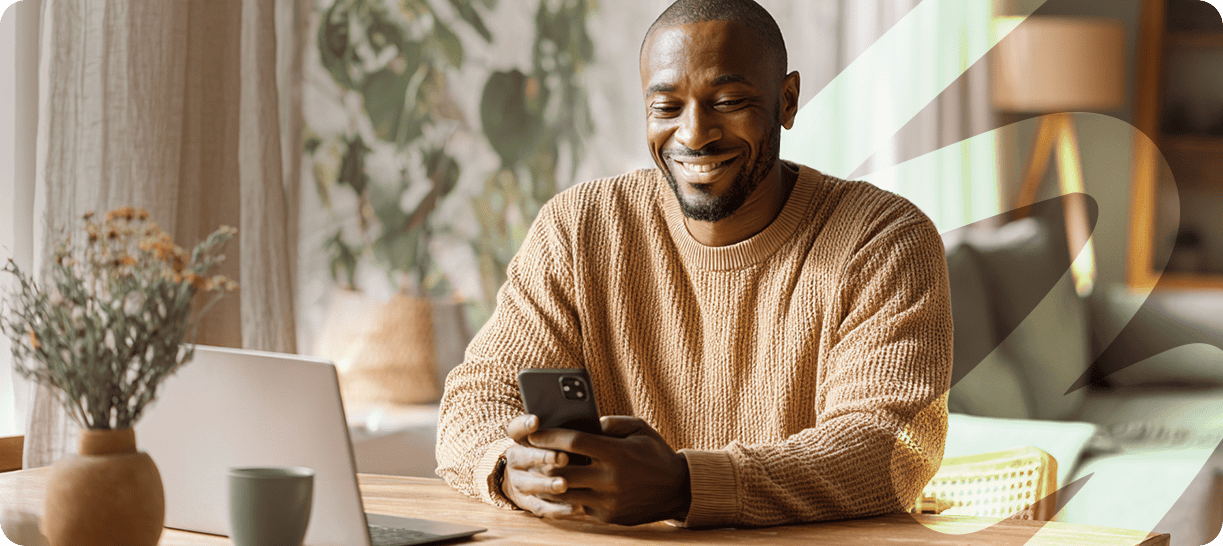 Smiling man using smartphone in a cozy home setting.