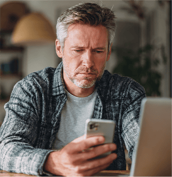Man looking at smartphone, possibly using Med Mend health app.